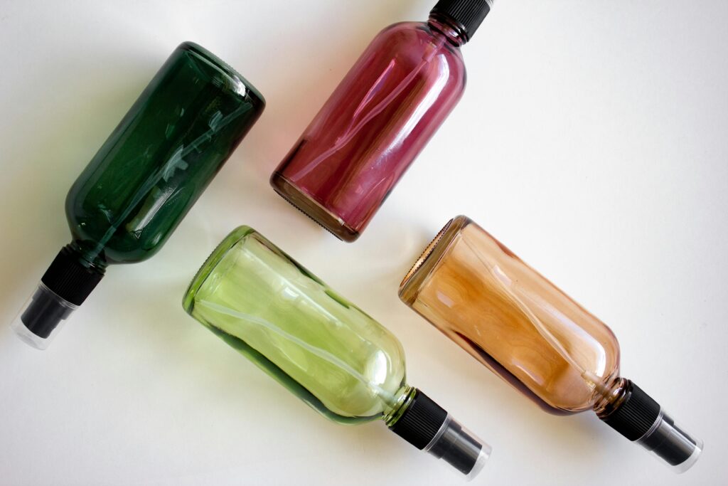 Four colorful spray bottles arranged on a white surface.