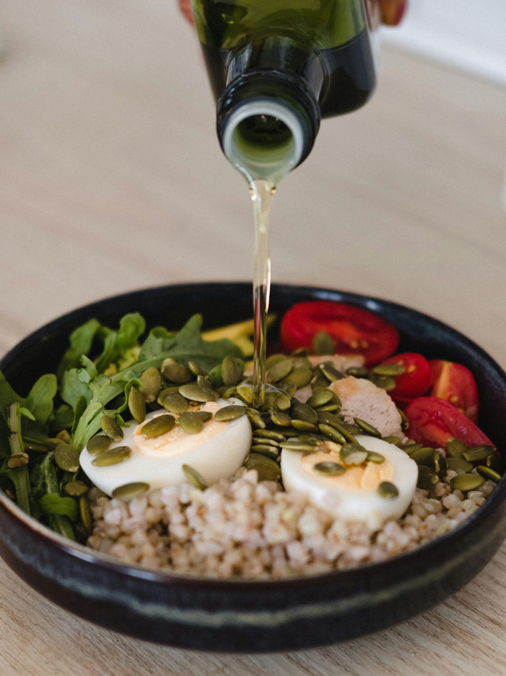Delicious whole grain salad with fresh vegetables, pumpkin seeds, and olive oil pour.