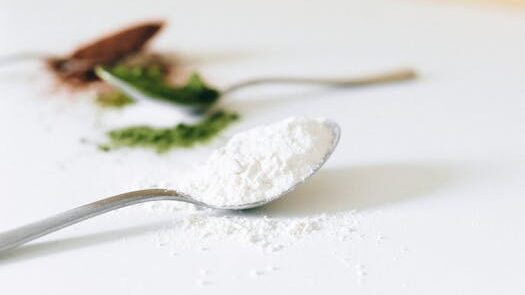 Close-up image of various colored powders on spoons with a blurred background.