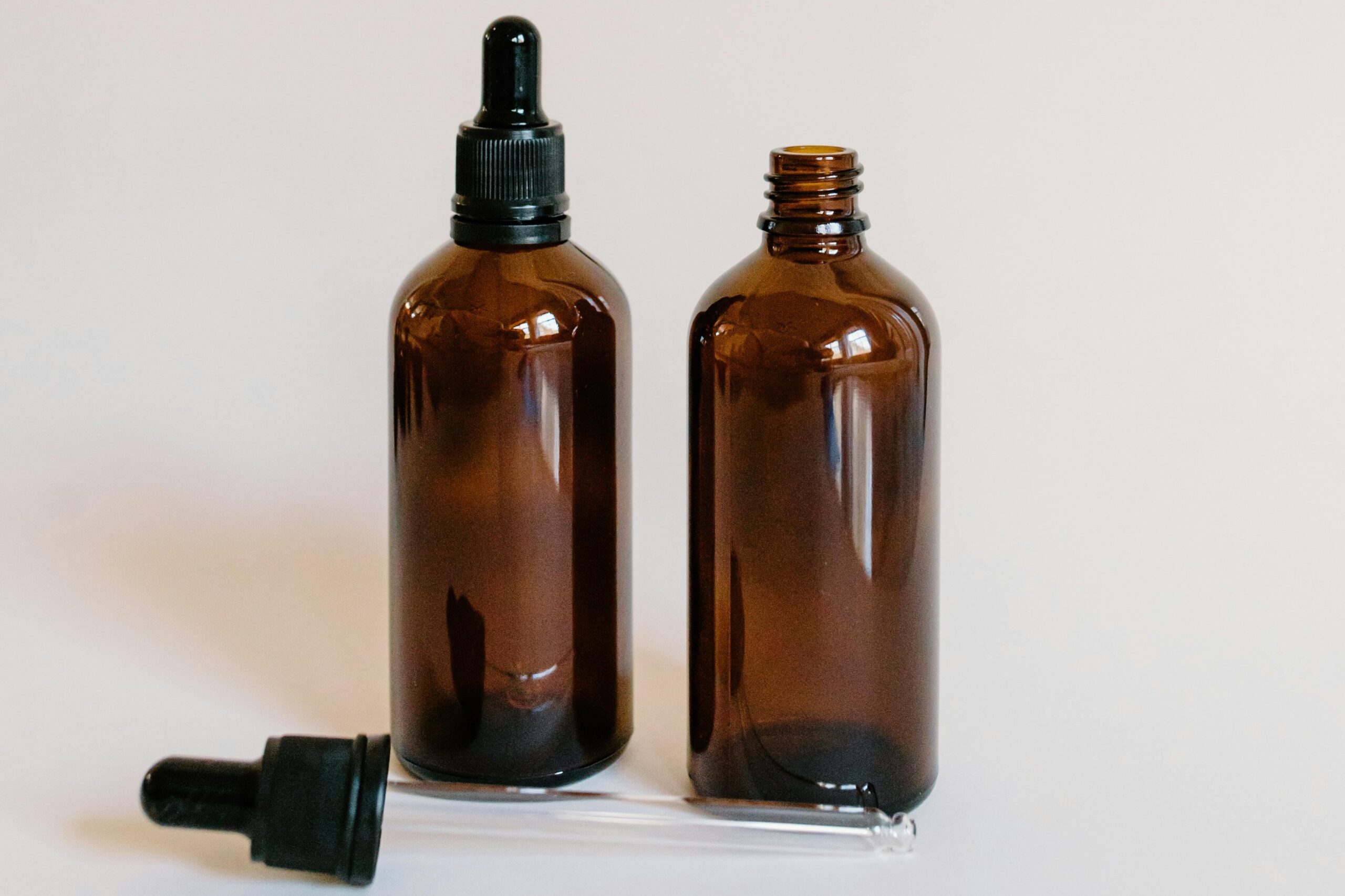 Brown glass dropper bottles on a white surface for aromatherapy and essential oils.