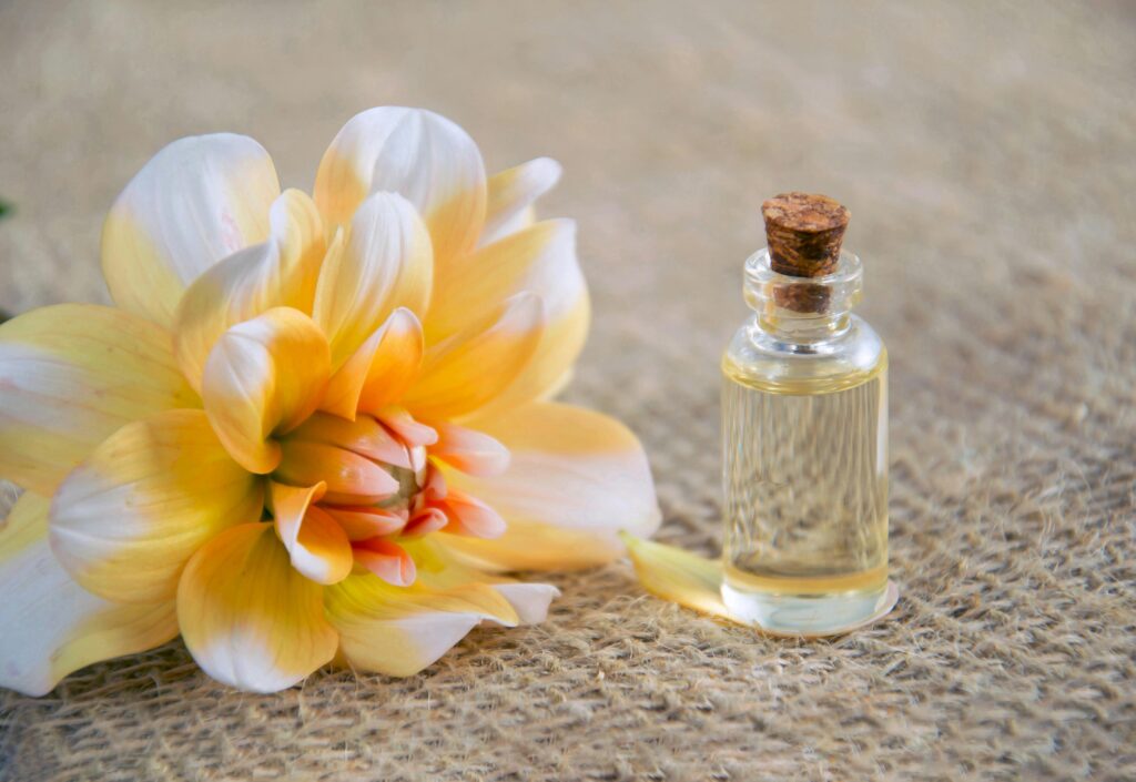 Close-up of a vibrant dahlia flower and glass bottle on burlap surface.